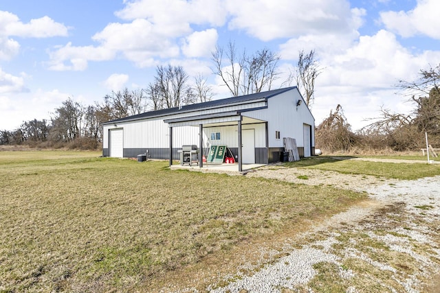 back of property featuring a detached garage, an outbuilding, and a yard