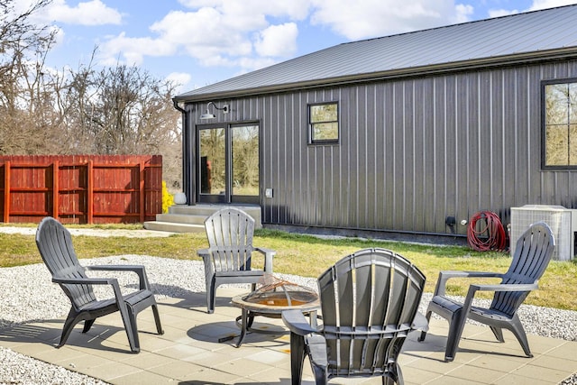 view of patio with central AC, fence, and a fire pit
