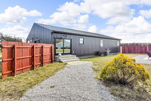 view of front facade featuring fence, board and batten siding, central AC, and metal roof
