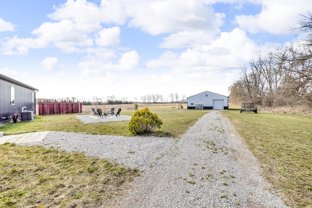 view of yard featuring a garage, central air condition unit, fence, an outdoor structure, and gravel driveway