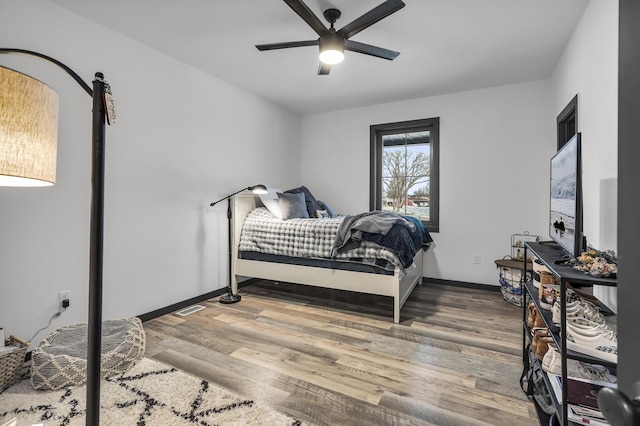 bedroom with a ceiling fan, baseboards, visible vents, and wood finished floors