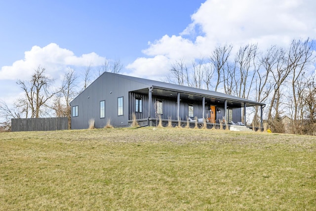 rear view of house with a lawn, board and batten siding, and a porch