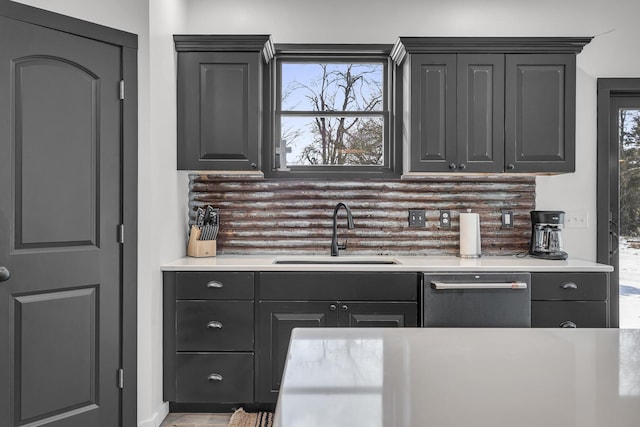 kitchen with light countertops, tasteful backsplash, a sink, and dishwasher