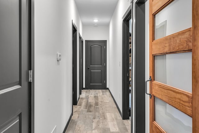 corridor with baseboards and light wood-style flooring