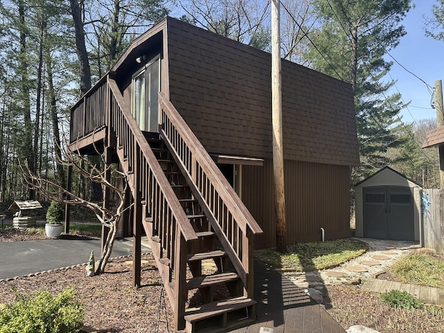 exterior space featuring an outdoor structure, a garage, a deck, stairs, and a storage shed