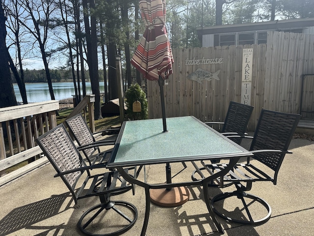 view of patio / terrace featuring a water view, fence, and outdoor dining space