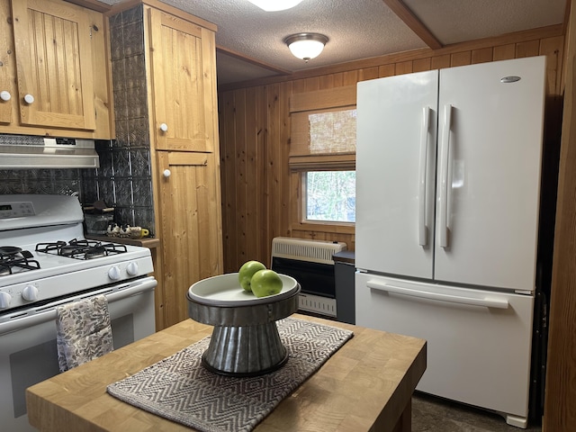 kitchen with heating unit, white appliances, butcher block countertops, a textured ceiling, and under cabinet range hood