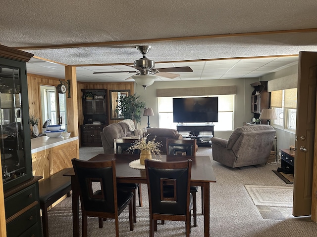 dining space featuring carpet floors, ceiling fan, and wood walls