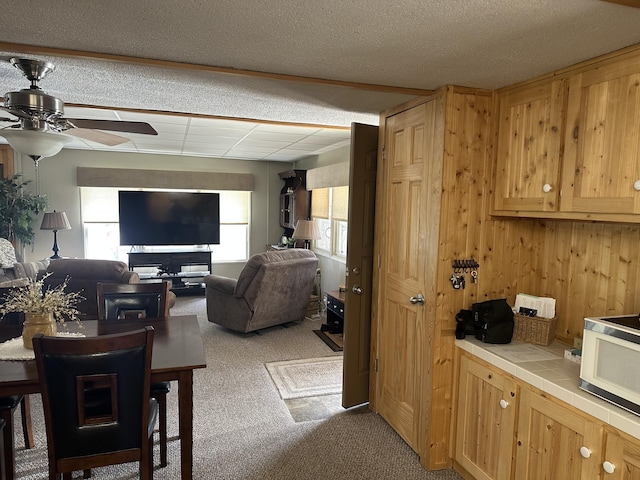 interior space featuring a healthy amount of sunlight, white microwave, tile countertops, and carpet flooring