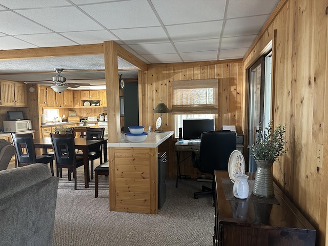 home office with wooden walls, a ceiling fan, a sink, and light colored carpet