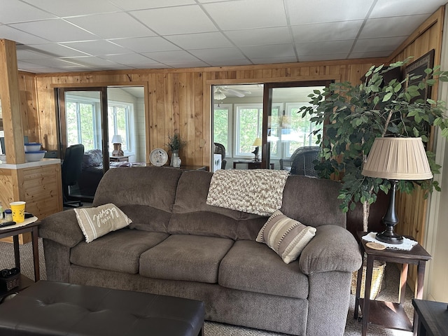 living area with plenty of natural light, ceiling fan, and wooden walls