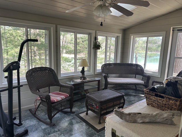sunroom featuring ceiling fan, outdoor lounge area, stone finish flooring, and lofted ceiling