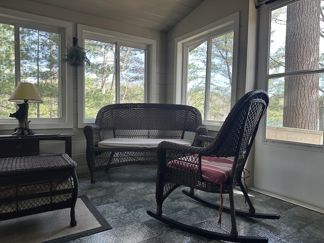 sunroom / solarium featuring a healthy amount of sunlight, stone finish floor, and lofted ceiling