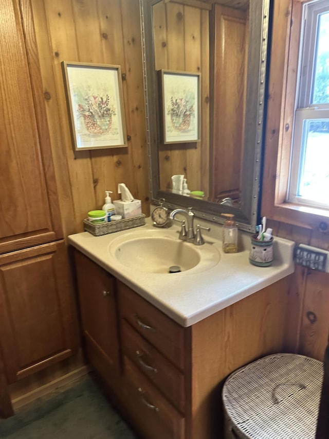 bathroom with wooden walls, a healthy amount of sunlight, and vanity