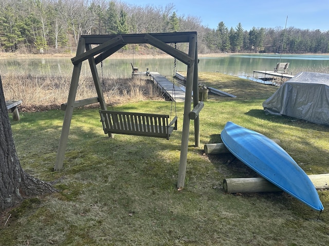 view of yard with a view of trees, a boat dock, and a water view