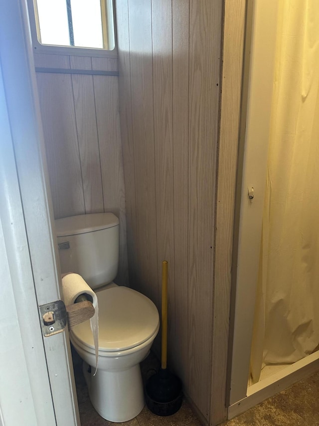 full bath featuring wood walls, walk in shower, and toilet