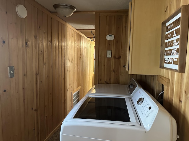 clothes washing area with separate washer and dryer and wooden walls