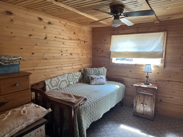 carpeted bedroom featuring wooden walls, ceiling fan, and wood ceiling
