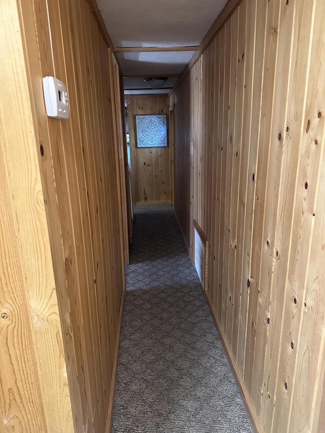 hall featuring carpet flooring and wooden walls