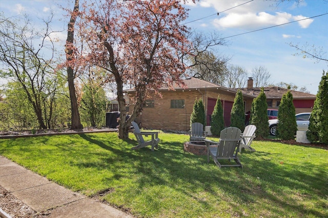 view of yard featuring an attached garage and a fire pit