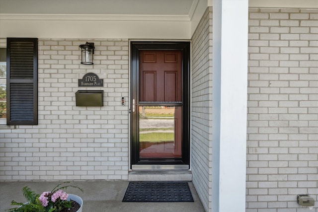 view of exterior entry featuring a porch and brick siding