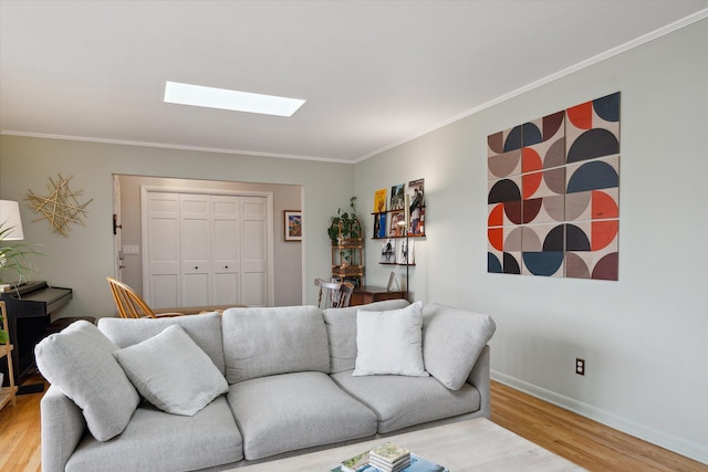 living room featuring baseboards, ornamental molding, light wood finished floors, and a skylight