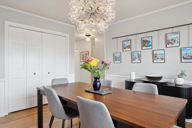 dining space featuring an inviting chandelier, ornamental molding, and light wood finished floors