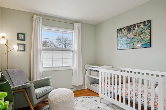 bedroom with a nursery area and wood finished floors