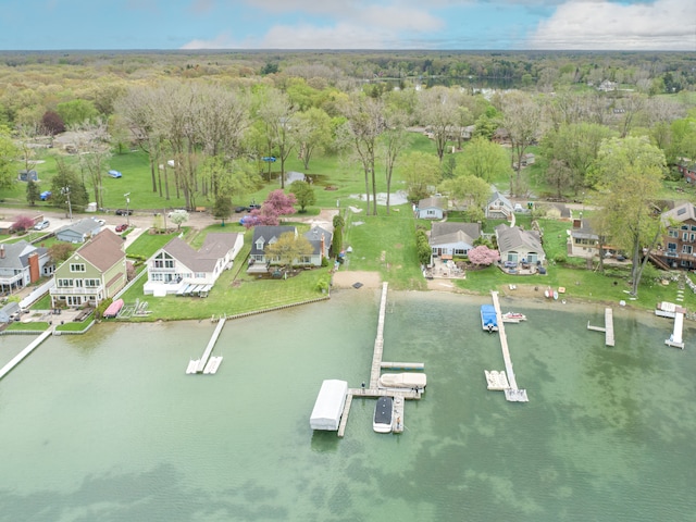 aerial view of property and surrounding area featuring a forest, a large body of water, and nearby suburban area