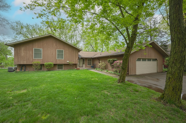 split level home with cooling unit, asphalt driveway, an attached garage, and a front lawn