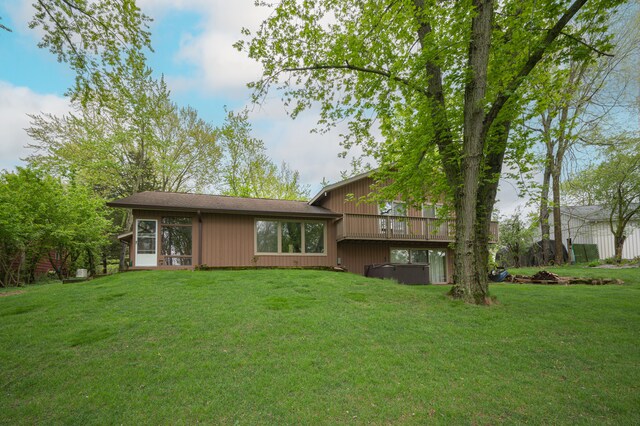 rear view of property with a hot tub and a yard