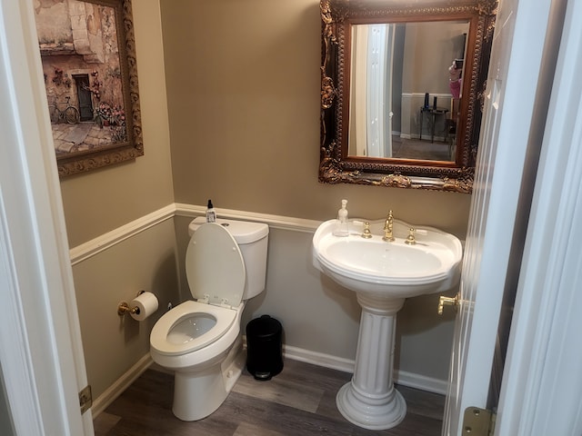 half bathroom featuring toilet, wood finished floors, and baseboards