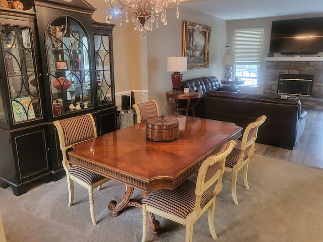 dining space with a notable chandelier, a fireplace, and wood finished floors