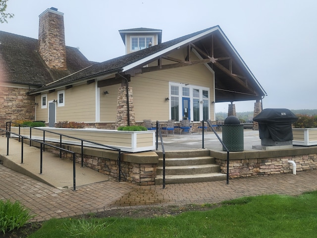 view of home's exterior featuring stone siding, a patio, and a chimney