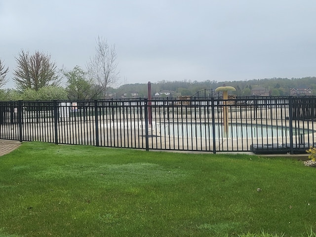 view of gate featuring fence, a fenced in pool, and a lawn