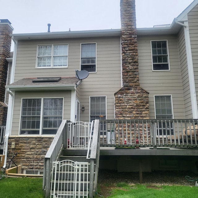 back of property with a deck and stone siding