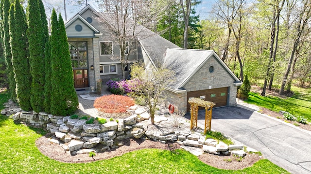 view of front of home featuring an attached garage, aphalt driveway, and stone siding