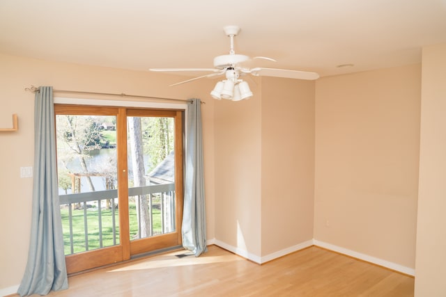 unfurnished room featuring visible vents, wood finished floors, baseboards, ceiling fan, and a water view