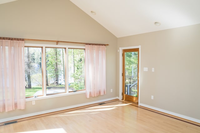 spare room featuring baseboards, high vaulted ceiling, wood finished floors, and visible vents