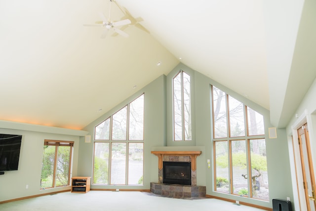 unfurnished living room featuring high vaulted ceiling, plenty of natural light, carpet floors, and a tile fireplace