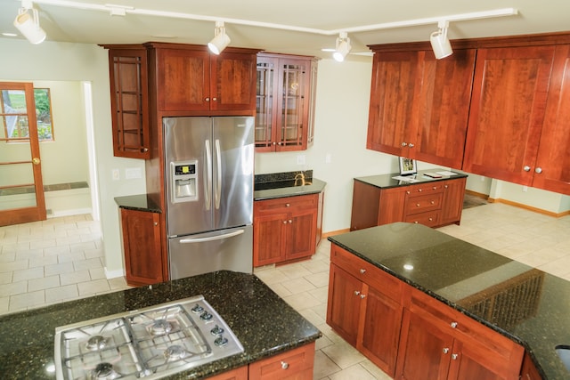 1151 Abseguami Trl, Lake Orion, MI 48362 - kitchen with stainless steel appliances, light tile patterned floors, dark stone countertops, glass insert cabinets, and track lighting