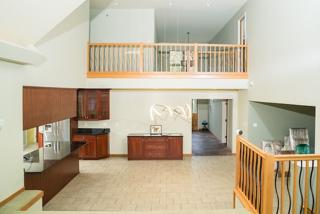 1151 Abseguami Trl, Lake Orion, MI 48362 - kitchen with a towering ceiling, dark countertops, glass insert cabinets, stainless steel fridge, and baseboards