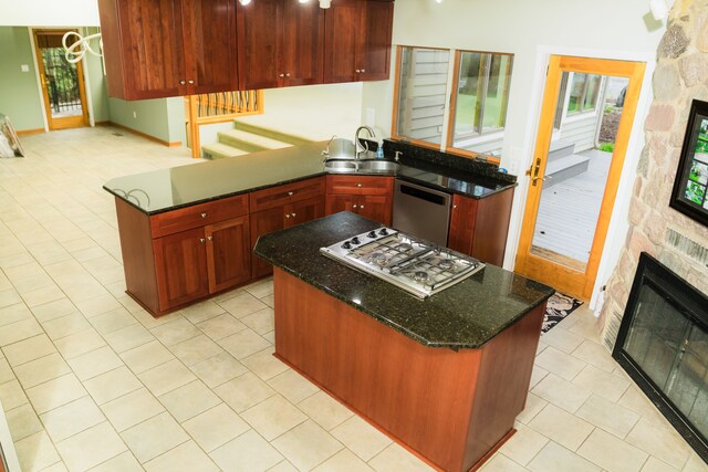 1151 Abseguami Trl, Lake Orion, MI 48362 - kitchen featuring stainless steel appliances, a stone fireplace, a sink, light tile patterned flooring, and reddish brown cabinets