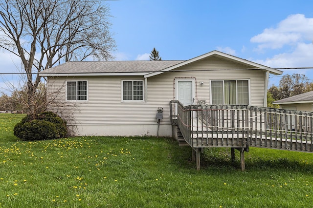 view of front of home with a deck, a front yard, and roof with shingles