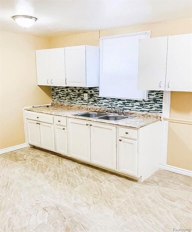 11696 Glastonbury Ave, Detroit, MI 48228 - kitchen featuring a sink, tasteful backsplash, baseboards, and white cabinetry