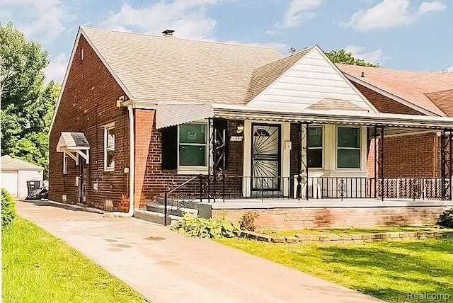 11696 Glastonbury Ave, Detroit, MI 48228 - view of front of house with brick siding, roof with shingles, a porch, and a front yard