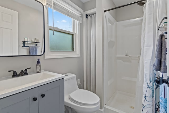 bathroom with a stall shower, toilet, and vanity