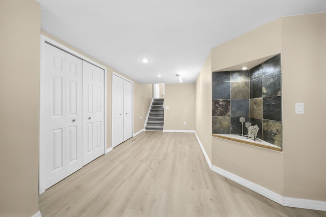 finished basement featuring light wood-style floors, recessed lighting, baseboards, and stairs