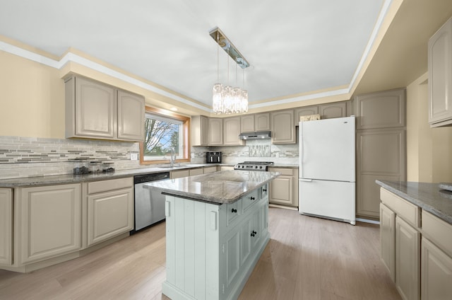 kitchen with an inviting chandelier, freestanding refrigerator, under cabinet range hood, a sink, and dishwasher