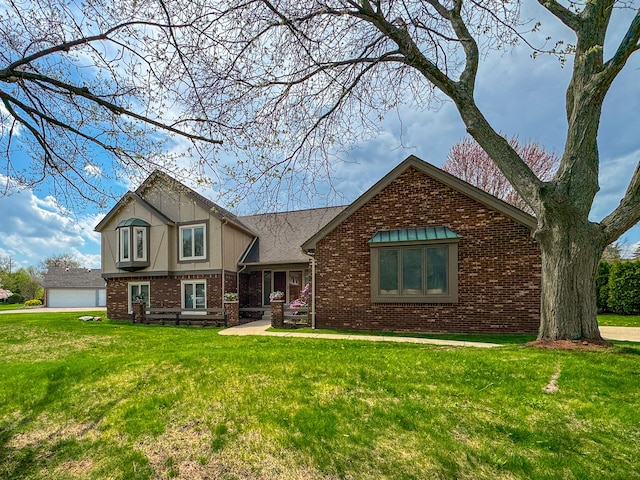 view of front of house featuring a detached garage, a front yard, and brick siding